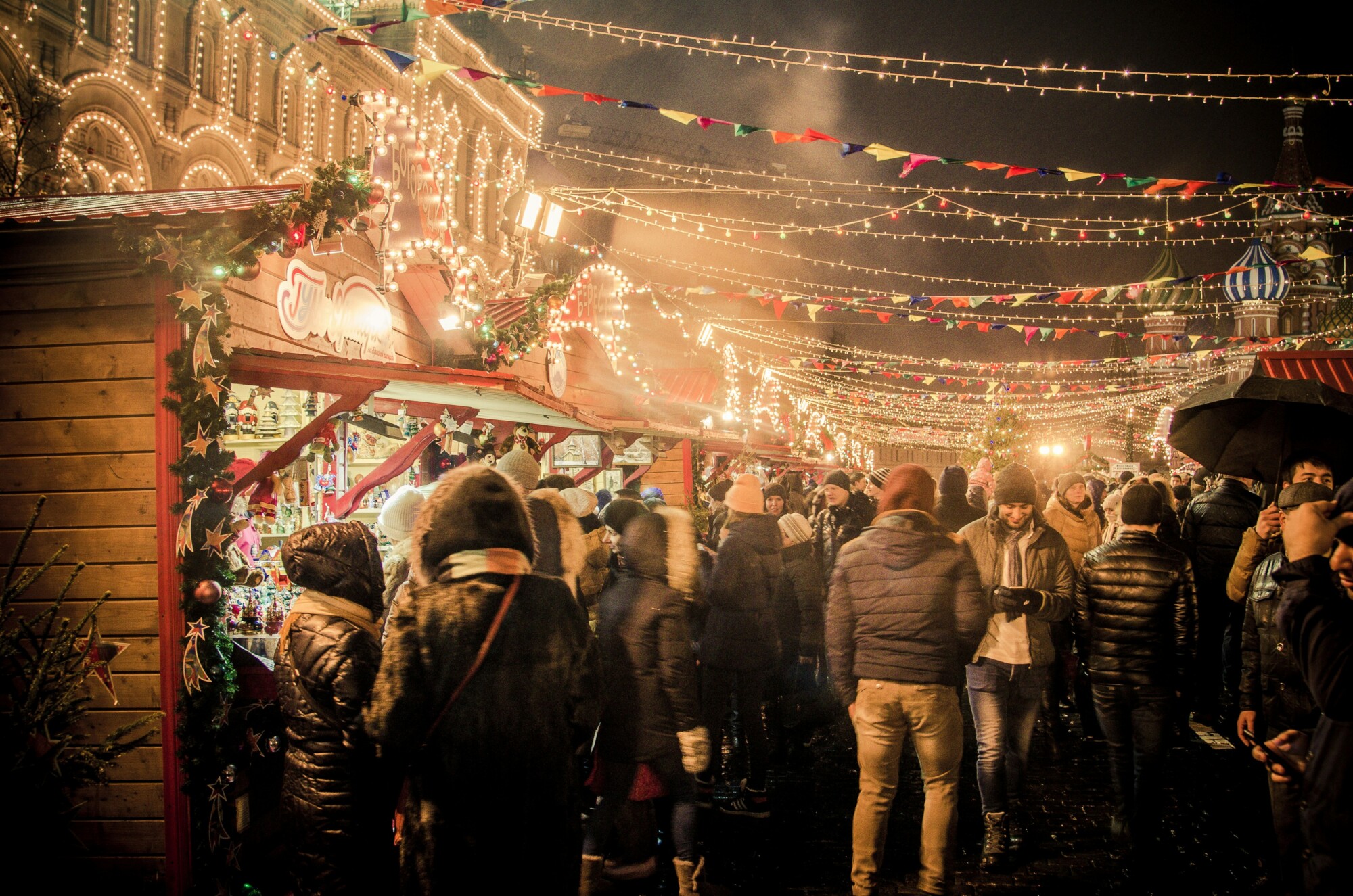 Belebter Weihnachtsmarkt mit Lichterketten und festlicher Stimmung.
