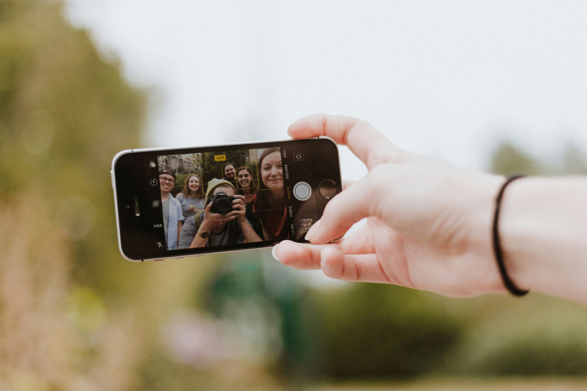 Eine Gruppe von Menschen macht ein Selfie mit einem Smartphone.