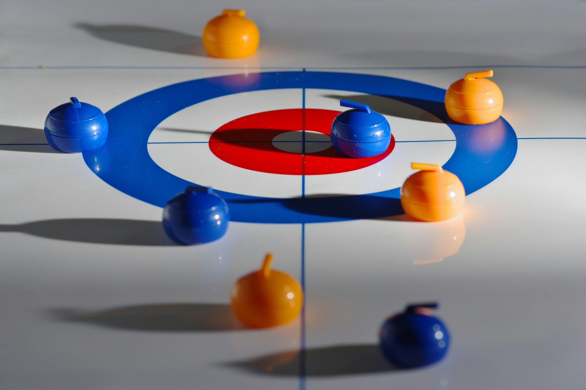 Mehrere Curling-Steine liegen auf der Zielscheibe eines Curling-Spielfelds