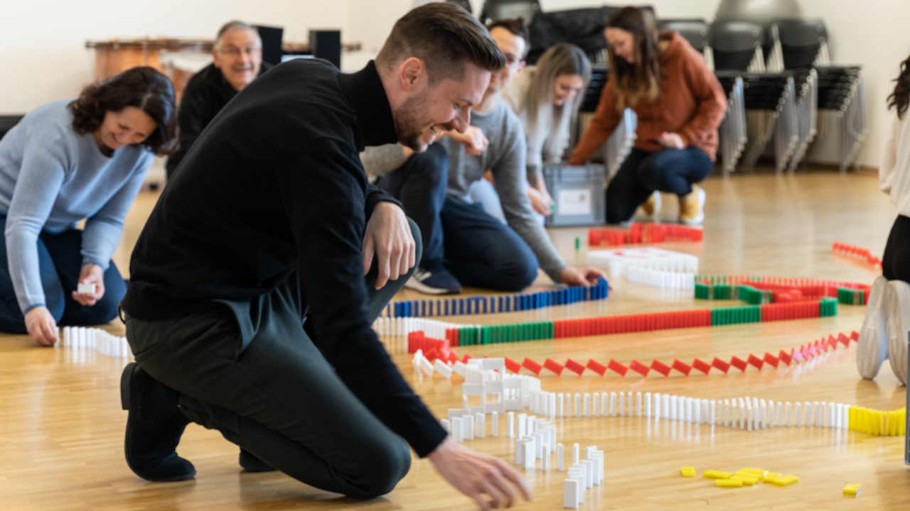 Domino-Workshop mit Kettenreaktion Das gemeinsame Aufbauen von Dominosteinen eignet sich ideal für Ihren nächsten Firmenevent. Schlüsselqualifikationen wie Gruppenzusammenhalt, Kommunikation, im Team etwas planen und realisieren werden hier auf die Probe gestellt. Entdecken Sie auf spielerische und unterhaltsame Weise die Welt der Kettenreaktionen mit Dominosteinen.