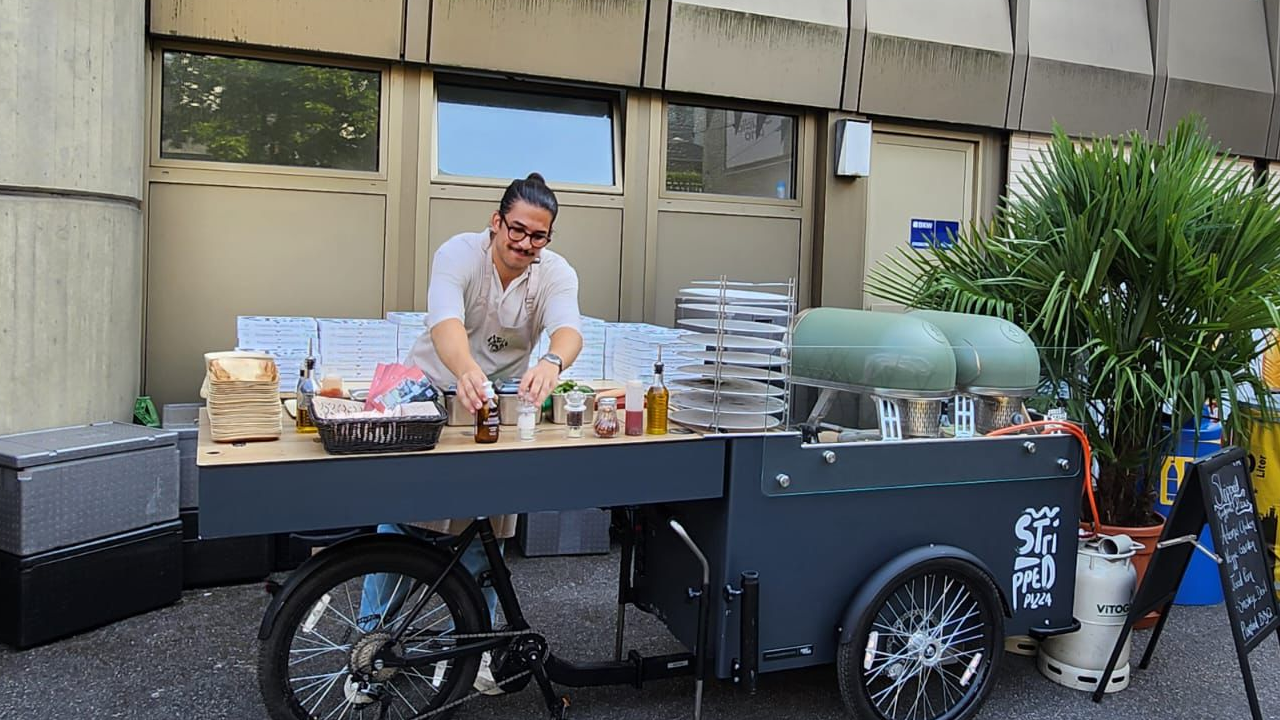 Erleben Sie Pizza-Genuss auf Rädern – mit unserem Pizza Bike! Machen Sie Ihren Firmenanlass unvergesslich: Wir kommen mit unserem einzigartigen Pizza Bike direkt zu Ihnen und backen unsere legendären Pizzas frisch, heiss und knusprig vor Ort. Dazu servieren wir köstliche Mini-Salate, feine Apéro-Snacks und Getränke ganz nach Ihrem Wunsch. Unser professionelles Team kümmert sich um den kompletten Service – für ein entspanntes und unkompliziertes Catering-Erlebnis, das Ihre Gäste begeistern wird. frisch, authentisch, mobil. Fragen Sie uns an und bringen Sie den Geschmack zu Ihrem Event!