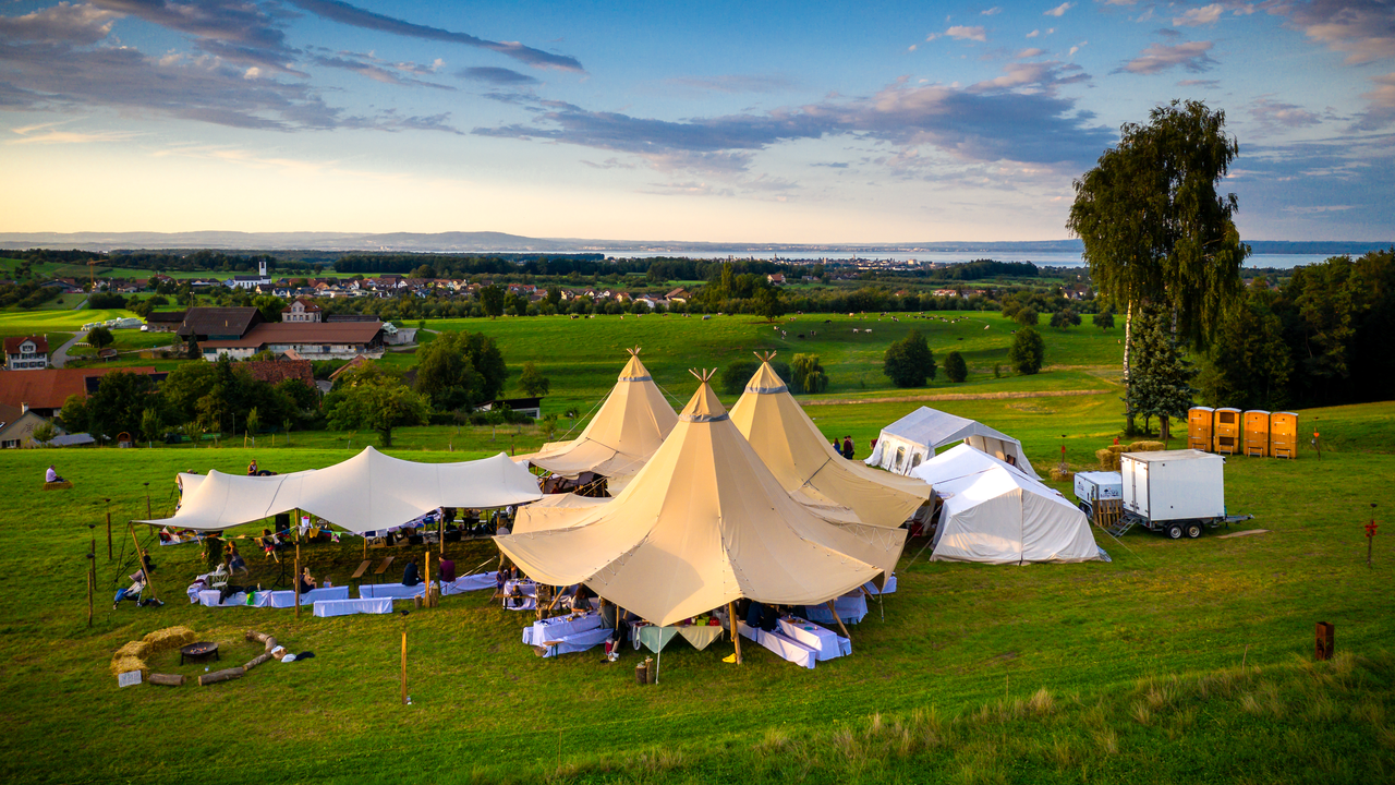 Event- und Outdoor-Tipis Ob Firmenevent, Romantikhochzeit oder Festival - besondere Anlässe sollten besonders gefeiert werden. Lassen Sie sich vom skandinavischen Lebensstil inspirieren und empfangen Sie Ihre Gäste in einer ganz besonderen Atmosphäre. Mit unseren spezielle Event-Tipis können wir im Freien wunderschöne Veranstaltungs-Locations bauen. Klein aber fein, ab 20 Personen oder beliebig zusammengehängt für Anlässe bis 1'000 Gäste. Die Zelte liefern wir auf Wunsch im Komplet-Paket mit Holzboden und passender rustikaler Bestuhlung.