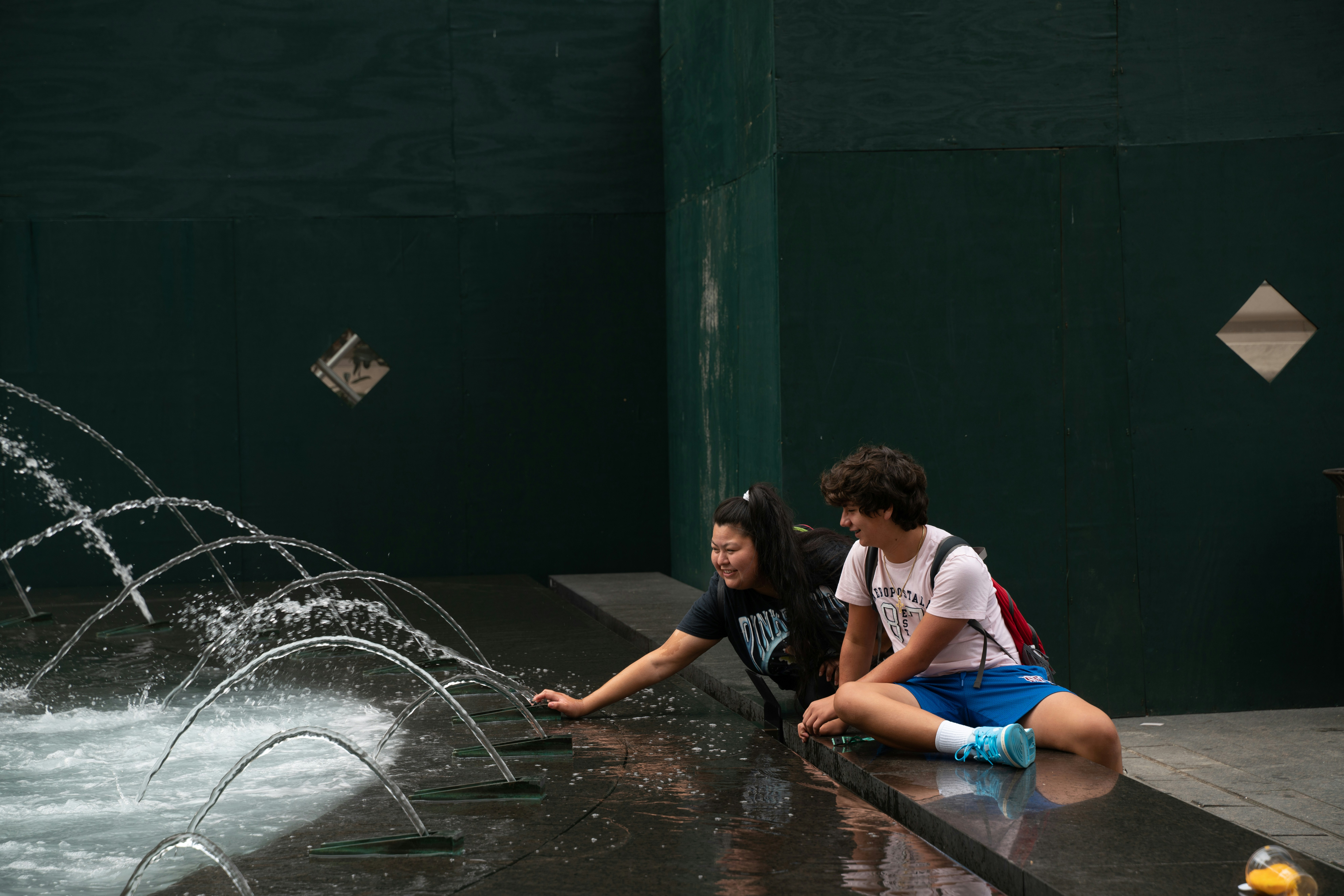 Menschen sitzen an einem Stadtbrunnen