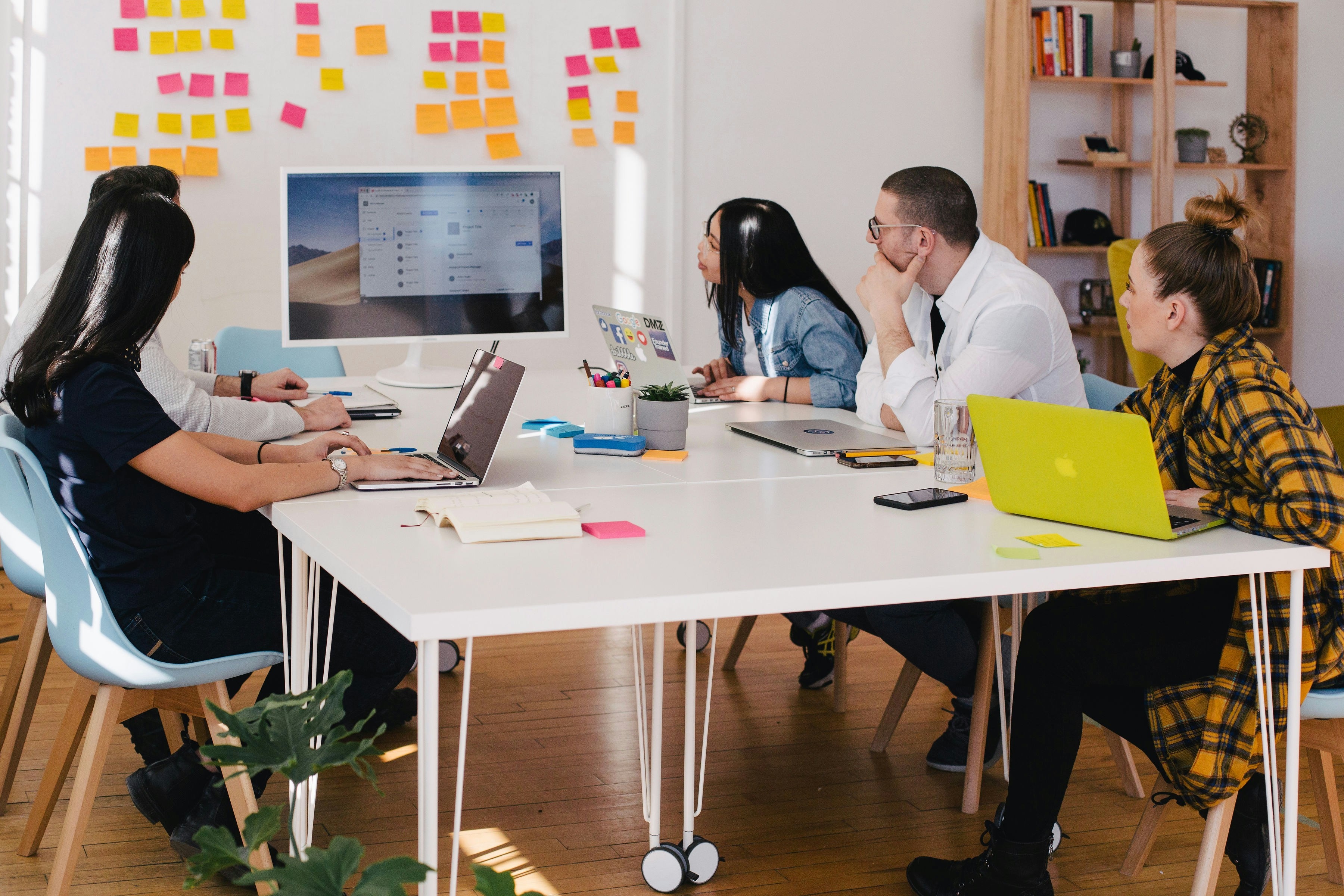 fünf Personen schauen gemeinsam an eine Wand mit Post-its